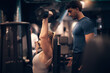 © Flamingo Images - Trainer working with a woman lifting dumbbells in the gym