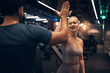 © Flamingo Images - Smiling woman high-fiving her trainer after a workout at the gym