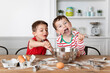 © Lisa Tichané - Funny siblings with messy face licking chocolate out of mixing bowl while baking