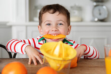 Smiling Little Boy Making Funny Face With Orange Peel In Mouth