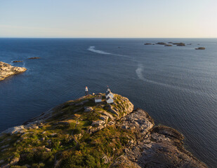 Wall Mural - The lighhouse from the small fishing town of Henningsvaer, Lofoten, Norway at sunset, from a drone point of view. Clear blue sky and crisp colors.