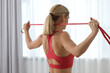 Fit woman doing exercise with fitness elastic band indoors