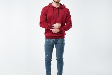 Canvas Print - A young man with a beard models a bright colorful red hoodie in a studio. The sweatshirt is a blank template for printing designs. The photo shows the front and back views of the streetwear fashion.