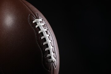 Wall Mural - American football ball on black background, closeup. Space for text