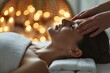 Primer plano de una mujer disfrutando de un masaje de cabeza en un ambiente de spa iluminado con luces suaves bokeh