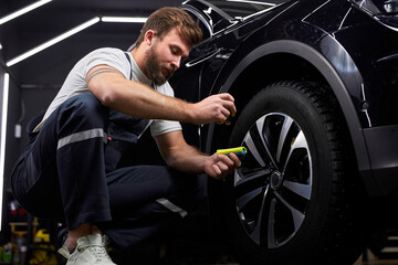 Wall Mural - Auto Mechanic Repairing Car Wheels, Using Liquid Oil For For Renovation, Apply It On Wheels. Copy Space. Auto Repairing Concept