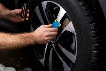 Poster - Professional Auto Mechanic Repair Man Using Liquid Oil For Lubricating Car Wheels In Auto Service, Close-up Photo Of Hands