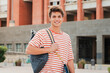 © Jose Calsina - Close up individual portrait of a handsome student young man standing at university campus. Happy teenage male smiling and looking at camera. Proud high school guy staring front carrying a backpack