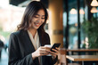 © gographic - Beautiful asian businesswoman using smart phone in coffee shop.