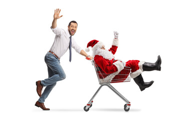 Canvas Print - Happy young man running and pushing Santa in a shopping cart