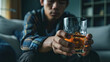 © Lakkhana - Health care alcoholism drunk, fatigue asian young man hand holding glass of whiskey, alone depressed male drink booze on sofa at home. Treatment of alcohol addiction, suffer abuse problem alcoholism.