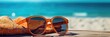 A sunglasses resting on a beach towel with the sea in the background