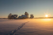 Bavarian church of Raisting with trees and snow and mist during winter and sunset, snow field with human footprints in the foreground, blue sky day, Bavaria Germany.