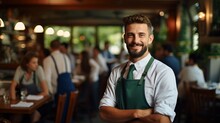 Confident Waiter Standing In Restaurant With Arms Crossed