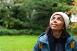 Beautiful latin woman with knit hat enjoying a walk through a beautiful lush park in Ireland