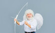 Valentines Day celebration. Happy bearded man in angel wings with bow and arrow. God of love. Valentine cupid in white wig shooting with bow. Arrow of love. February 14. Male angel with bow and arrow.