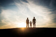 © Davide Angelini - Silhouette of happy family watching the sunset together - Mother, father and child son having fun outdoors enjoying family time - Family, love, mental health and happy lifestyle concept
