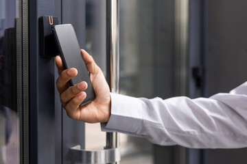 Hand man closely with the phone, the businessman uses the application on the smartphone to remove the door opening of the house, office.