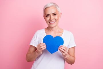 Sticker - Portrait of candid sincere person with white hairdo dressed stylish t-shirt hands hold blue heart postcard isolated on pink background