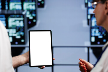 Poster - Close up of mock up tablet used by collaborating colleagues in cloud computing business server farm delivering massive computational power, capable of processing and storing vast amounts of datasets