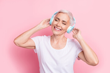 Poster - Photo portrait of attractive pensioner woman touch earphones enjoy listen music wear trendy white clothes isolated on pink color background