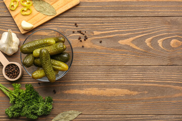 Wall Mural - Glass bowl with pickled cucumbers and different spices on wooden background