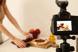 Woman making tasty apple pie on display of professional photo camera in studio