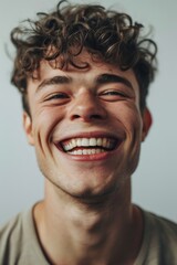 Aufkleber - A young man with curly hair smiling for the camera. Suitable for various uses