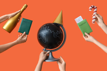 Wall Mural - Female hands holding passports with globe and champagne on orange background. New year vacation concept