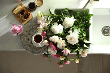 Canvas Print - Beautiful peonies and breakfast on kitchen counter, flat lay