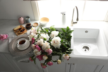 Canvas Print - Beautiful peonies and breakfast on kitchen counter, above view