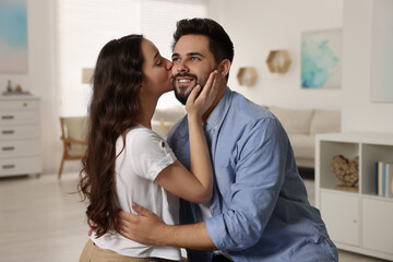 Poster - Cute couple. Woman kissing her smiling boyfriend at home