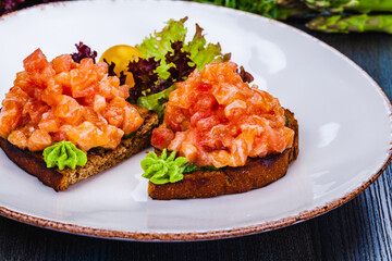 Sticker - Healthy toasts with rye bread with salmon, avocado mousse, lettuce on white plate.