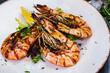 Grilled tiger prawns with greens on white plate