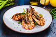 Grilled tiger prawns with greens on white plate