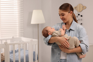 Wall Mural - Mother holding her cute newborn baby in child's room