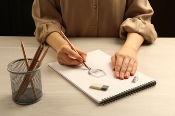 Wall Mural - Woman drawing glass of wine with graphite pencil at light wooden table, closeup