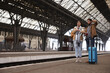 © New Africa - Being late. Worried couple with suitcase waiting at train station, space for text