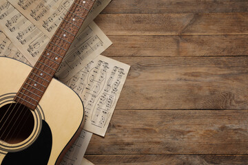 Sticker - Paper sheets with music notes and acoustic guitar on wooden table, top view. Space for text