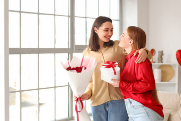 Canvas Print - Young lesbian couple with gift and roses at home on Valentine's Day