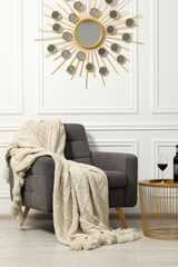 Sticker - Comfortable armchair, blanket and wine on side table near white wall. Interior design