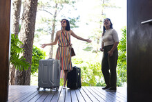 Happy Asian Female Friends With Luggage Admiring Garden And Home