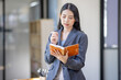 © David - Thinking of asian young business woman working with read the note recorded in the business plan laptop computer in her workplace
