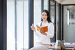 © David - Thinking of asian young business woman working with read the note recorded in the business plan laptop computer in her workplace