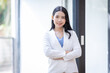 © David - Young happy business asian woman with arms crossed standing int her office and looking at camera.
