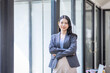 © David - Young happy business asian woman with arms crossed standing int her office and looking at camera.