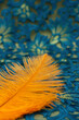Orange feather of a bird on a background of beautiful fabric with lace. Poster for interior. Feather for decoration.