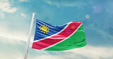Fototapeta  - Namibia national flag cloth fabric waving on the sky - Image
