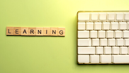 Poster - Closeup view of a wooden cube with Learning word and computer keyboard