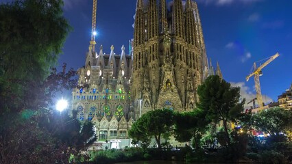 Wall Mural - Sagrada Familia: Day to Night Transition Timelapse of the Iconic Roman Catholic Church in Barcelona, Spain. Spires and Cranes Stand Against Reflecting in the Tranquil Waters of the Nearby Lake